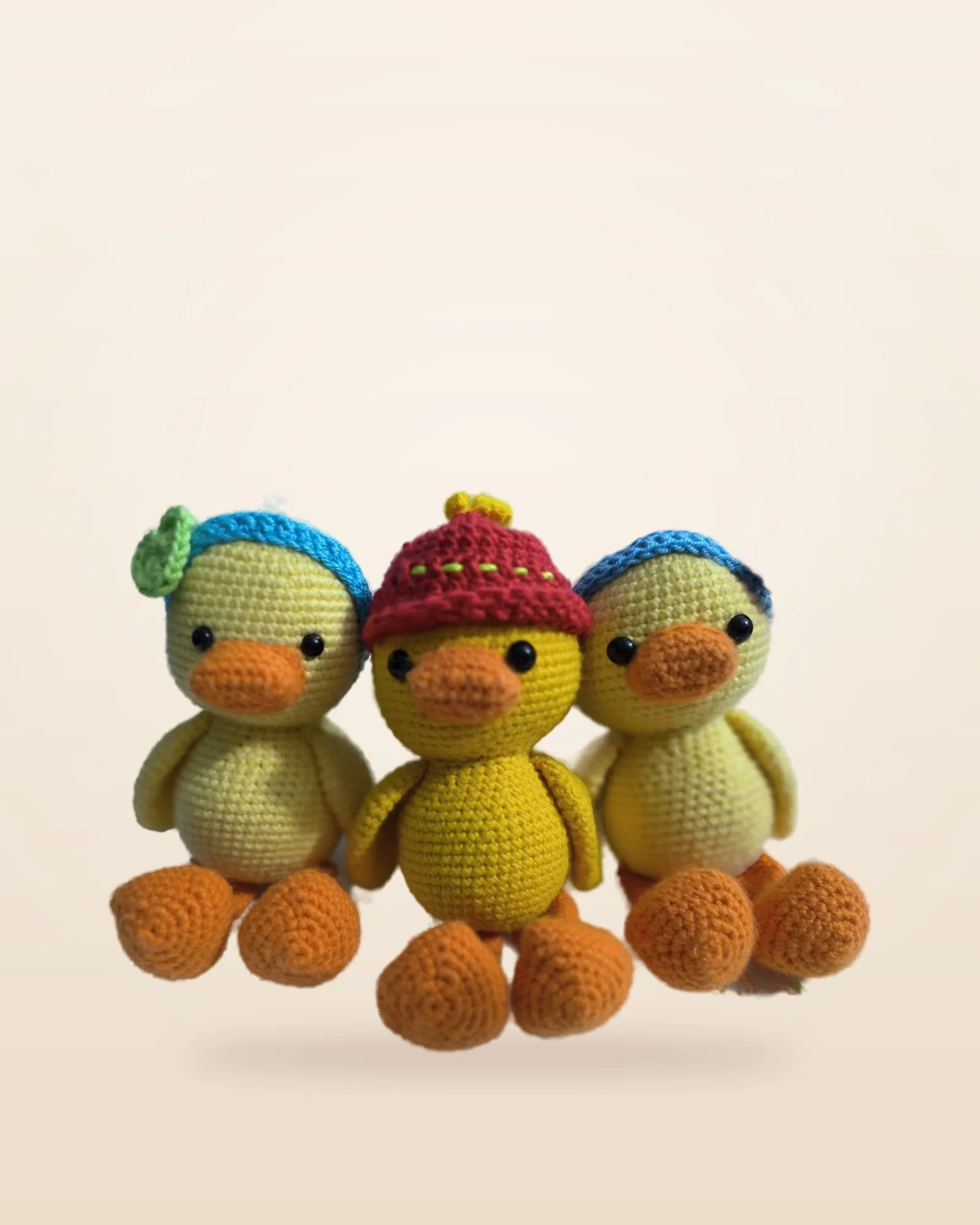 Tres patitos de crochet amarillos con gorros azul y rojo
